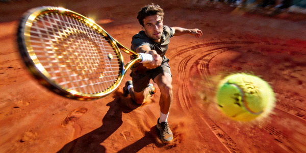 网球运动员在红土场上奋力击球的动作瞬间